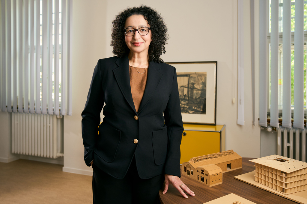 Porträt einer Frau mit lockigem Haar und Brille.